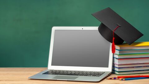 Fachtierärztliche Weiterbildung Auf einem Notebook hängt seitlich ein Doktorhut und daneben liegt ein Stapel Bücher