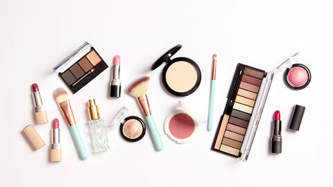 Verschiedene Kosmetikartikel Lidschatten, Puder, Make up, Lippenstift und Kosmetikpinsel liegen ausgebreitet mit Blick von oben