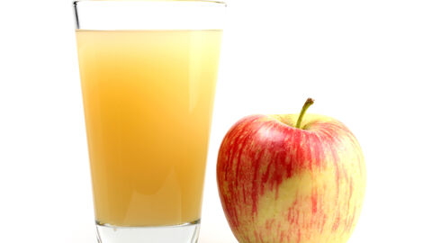 Ein Glas naturtrüber Apfelsaft und daneben ein Apfel