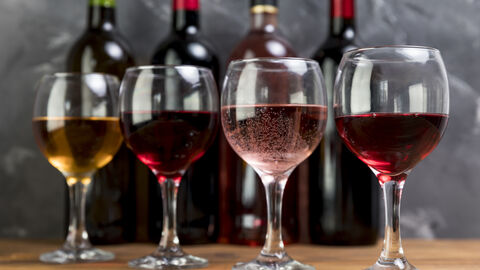 Verschiedene Weine in Gläsern und im Hintergrund die dazugehörigen Weinflaschen 