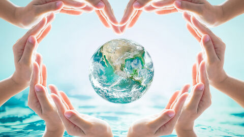 Herz aus Händen um eine Weltkugel