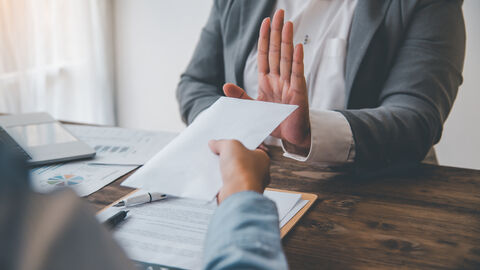 Eine Mensch weist einen angebotenen Briefumschlag mit ausgestreckten Händen zurück