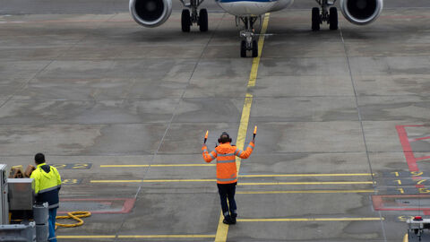 Import von Forschungsmaterialien Ein Flugzeug wird von einem Mitarbeiter auf dem Flugfeld auf seine Halteposition eingewiesen