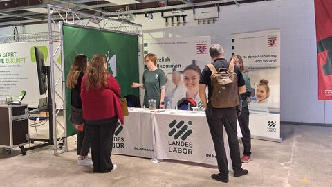 Zukunftssicher und spannend: Chemie- und Biologielaborant im Hessischen Landeslabor Messestand des LHL auf einer Ausbildungsmesse. Interessenten stehen vor dem Messestand und lassen sich beraten.