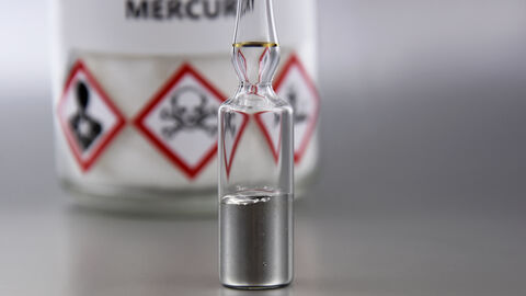 Eine Quecksilberampulle steht vor einem Warnhinweis für Quecksilber