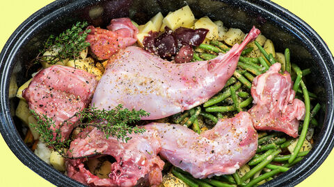 Zu Ostern Hase auf dem Tisch - Hase und Kaninchen als Lebensmittel Es liegen rohe Stücke von einem Kaninchen in einer Bräterpfanne auf verschiedenem Gemüse