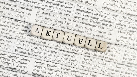 Textschnipsel liegen unter Buchstabenwürfel, die das Wort Aktuell formen