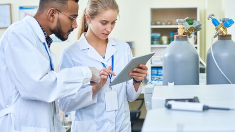 Auszubildene schauen gemeinsam im Labor auf ein Tablet