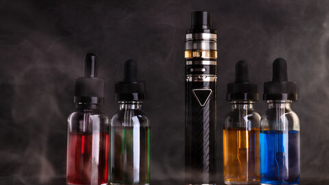 Elektronische Zigarette und Flaschen mit Dampfflüssigkeit auf schwarzem Hintergrund
