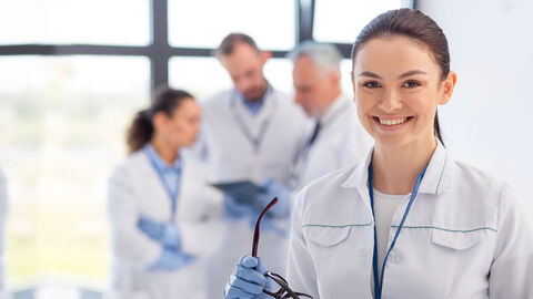 Frau im weißen Kittel lächelt in die Kamera