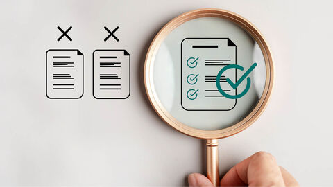 Eine Mensch hält eine Lupe in der Hand, die ein akkreditiertes Dokument vergrößert